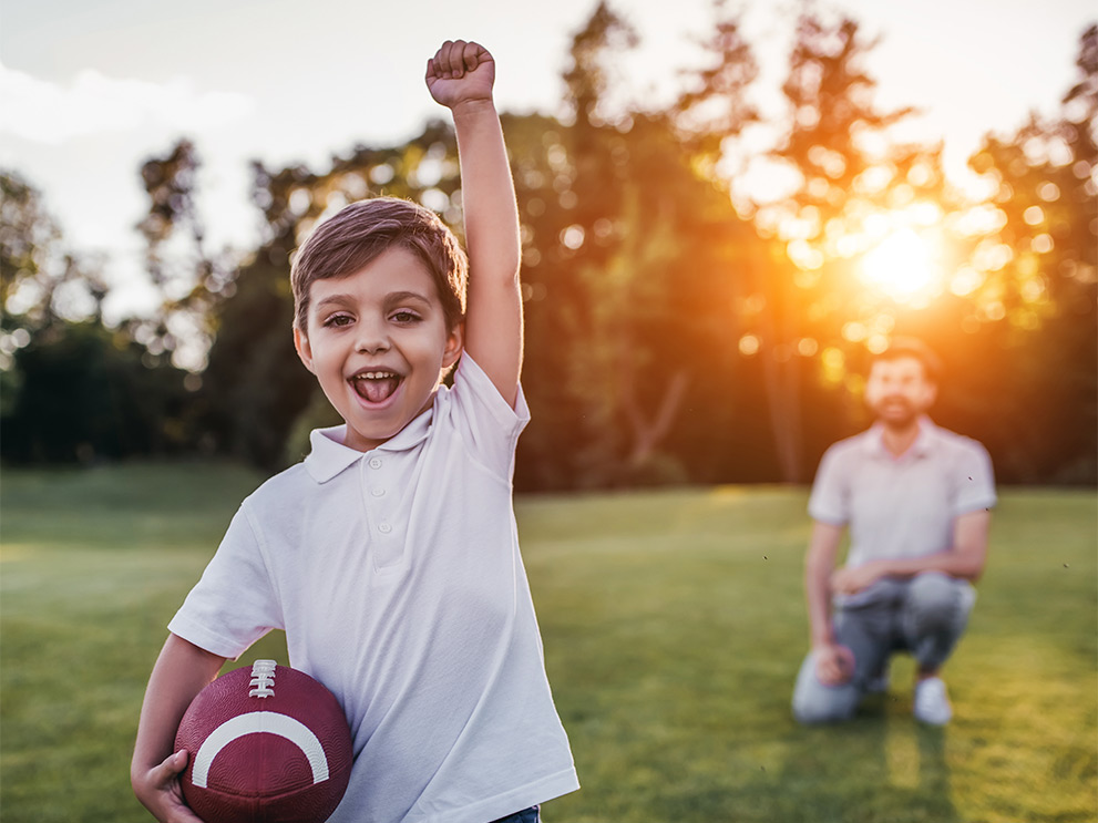 Young boy playing football with his dad